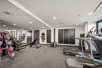 Well-equipped fitness center with assortment of medicine balls, free weights, treadmills, and universal exercise equipment